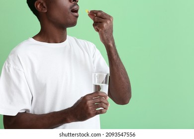 African-American Man Taking Fish Oil On Color Background