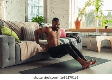 African-american man teaching at home online courses of fitness, aerobic, sporty lifestyle while being quarantine. Getting active while isolated, wellness, movement concept. Training upper body.
