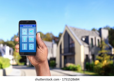 African-American man using home security app on smartphone outdoors, closeup. Space for text