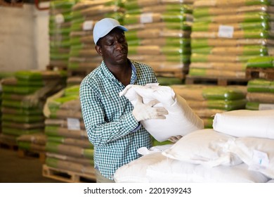 African-american Man Working In Warehouse, Lifting Heavy Bag. Storehouse Worker Carrying Bag.