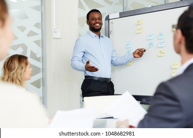 African-american Manager Standing By Whiteboard And Presenting His Ideas For New Project For Company