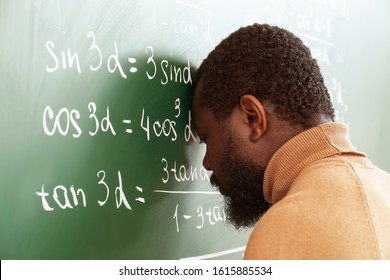 African-American math teacher in despair near blackboard
