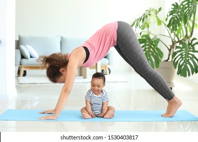 African-American mother training with cute little baby at home