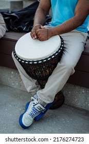 An African-American Plays A Drum, The Hands Of A Black Guy Lie On The White Deck Of An African Djembe Drum, A Street Musician, A Part Of A Human Body. High Quality Photo