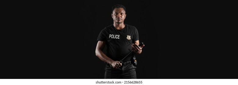 African-American police officer with baton on dark background
