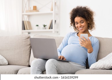 African-american pregnant girl using laptop and cellphone, resting on sofa, copy space - Powered by Shutterstock