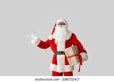 African-American Santa Claus with gift on light background - Powered by Shutterstock