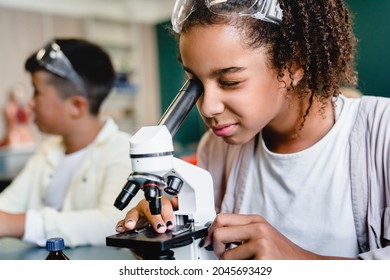 African-american schoolgirl pupil student using working with microscope at biology chemistry lesson class at school lab. Science lesson concept - Powered by Shutterstock