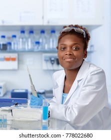 African-american Scientist Or Graduate Student In Lab Coat And Protective Gloves Smiles At The Camera