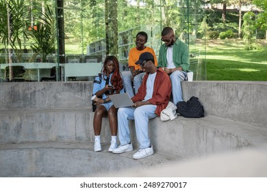 African-American smiling guy explaining difficult study topic to classmates using laptop. Satisfied man showing groupmates presentation, article, telling complex educational material, doing homework - Powered by Shutterstock