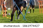 African-American soccer player on training drill. Legs of footballer running on grass practice field. Obstacle course in soccer football. Player running in sports cleats