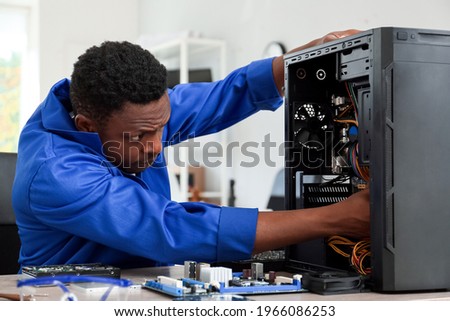 African-American technician repairing computer in service center