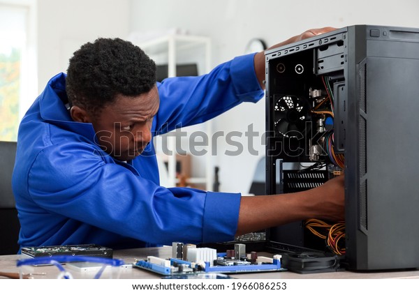 African-American technician repairing computer in\
service center
