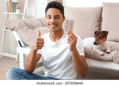 African-American Teenage Boy With Fish Oil Pills And Cute Dog At Home