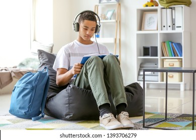 African-American teenage boy reading book at home