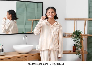 African-American Teenage Girl Brushing Teeth Near Mirror In Bathroom