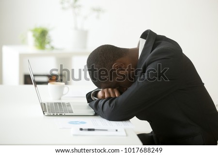 African-american tired deprived businessman feeling lack of sleep having nap at workplace, black restless entrepreneur hopeless by bankruptcy or debt, depressed investor desperate about failure