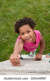 An African-American Toddler Climbing A Play Wall.