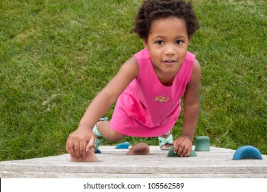 An African-American Toddler Climbing A Play Wall.