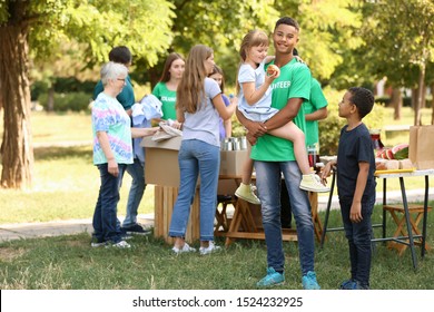 African-American volunteer with poor little children outdoors