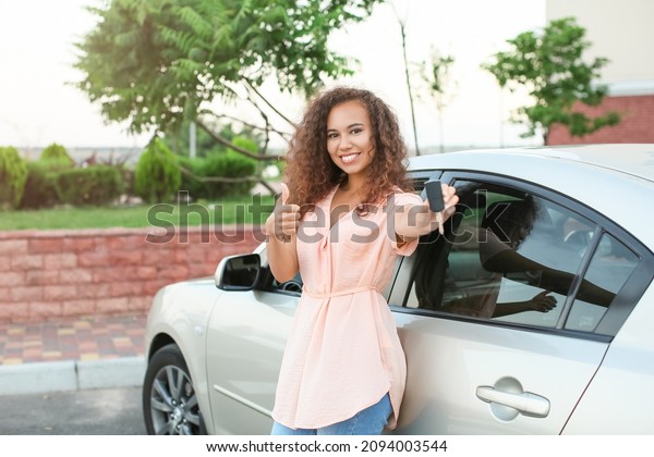 African-American woman with car key fob showing\
thumb-up\
outdoors