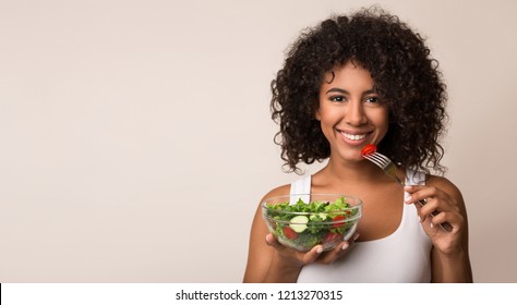 African-american woman eating vegetable salad over light background with copy space - Powered by Shutterstock