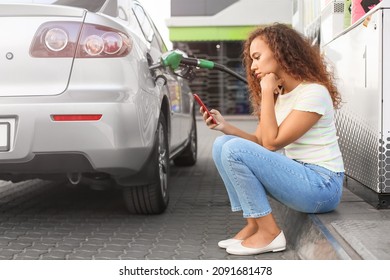 African-American Woman Filling Up Car Tank At Gas Station