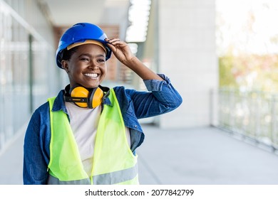 A African-American Woman In Her 30s Working At A Construction Site, Wearing A Hardhat, Safety Goggles And Reflective Vest. She Is Looking Over The Camera With A Confident Expression, Showing Thumb Up.