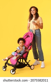 African-American Woman And Her Cute Baby In Stroller On Color Background