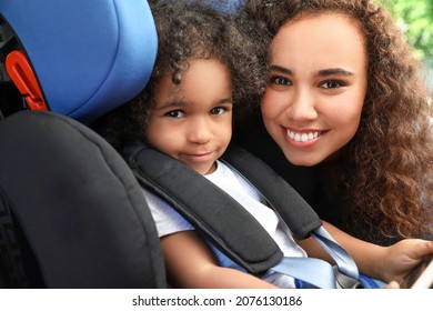 African-American Woman And Her Little Daughter Fastened In Car Safety Seat