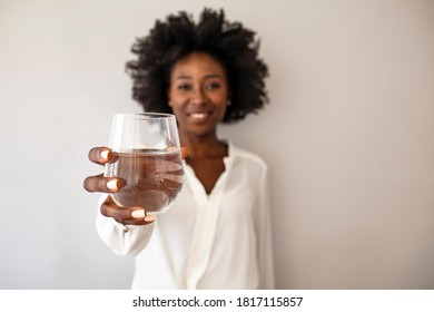 African-American Woman holding glass of water. Happy beautiful young woman holding drinking water glass in her hand. Health care concept. Health trend