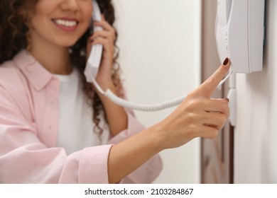 African-American woman pressing button on intercom panel indoors, closeup