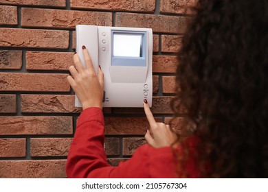African-American woman pressing button on intercom panel indoors