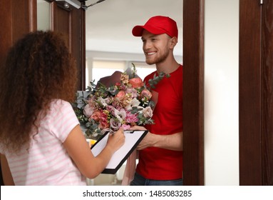 African-American Woman Receiving Flower Bouquet From Delivery Man Indoors