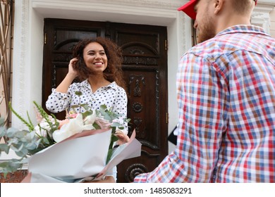 African-American Woman Receiving Flower Bouquet From Delivery Man At Door