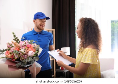 African-American Woman Receiving Flower Bouquet From Delivery Man Indoors