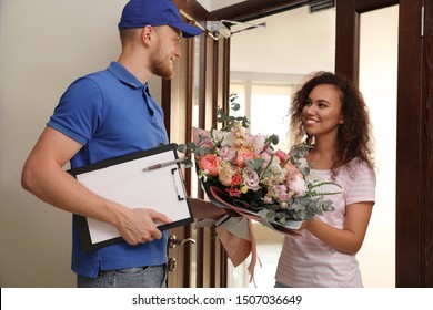 African-American Woman Receiving Flower Bouquet From Delivery Man Indoors