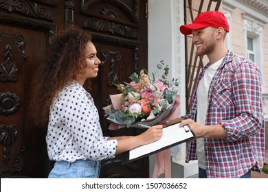 African-American Woman Receiving Flower Bouquet From Delivery Man At Door