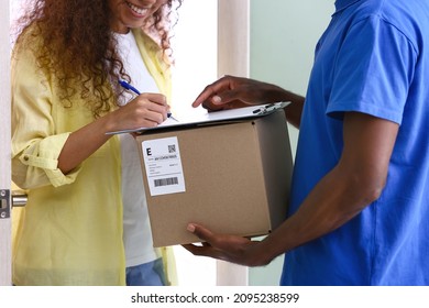 African-American woman receiving parcel from courier of delivery company