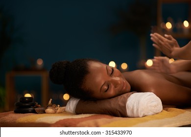 African-American woman receiving professional back massage in spa salon