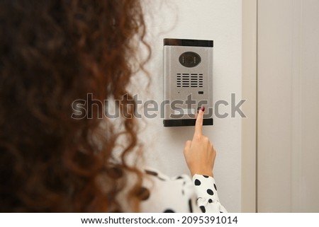 African-American woman ringing intercom with camera in entryway, closeup