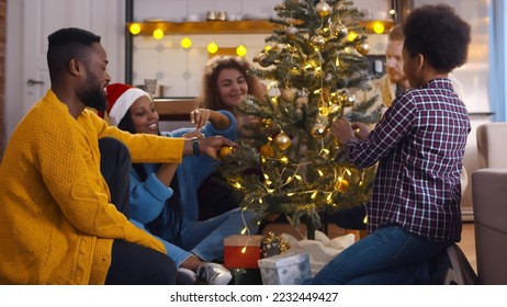 African-American-american family with caucasian friends couple decorating christmas tree together. Portrait of young diverse people and kid hanging decorations on christmas tree - Powered by Shutterstock