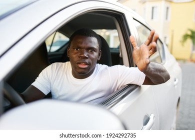 an african-looking man driving a car peeking out of an open window