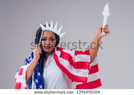 afro american army latin in a white medical gown clothes dreadlocks makeup and big lips with a paper crown and a torch on white background in studio with american flag,independence day usa 4th of july