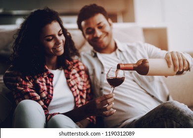 Afro American Couple Drinking On A Couch. Weekend Concept. Chilling On Sofa. Holiday Resting. Smiling Together. Having Fun. Romantic Date. Cheerful Sweethearts. Bottle Of Wine. Happy Family.