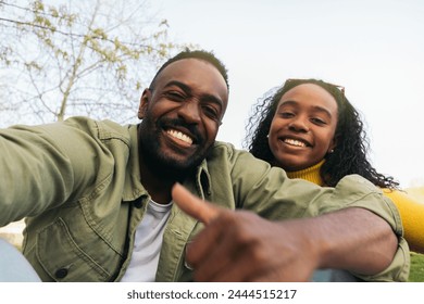 afro american couple taking a selfie sitting in a park - Powered by Shutterstock