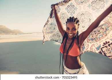 Afro american female standing on the seaside with her scarf. Beautiful woman standing on the beach with fabric.