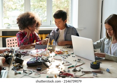 Afro American girl and Asian boy schoolkids using tablet device developing program for software robotics engineering and building at school lab. AI technologies development. STEM education. Vertical. - Powered by Shutterstock