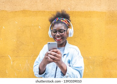 Afro American Girl Using Mobile Phone Outdoors. Latin American Teenager Having Fun. Black Girl Using Cellphone And Laughing.Youth Concept.