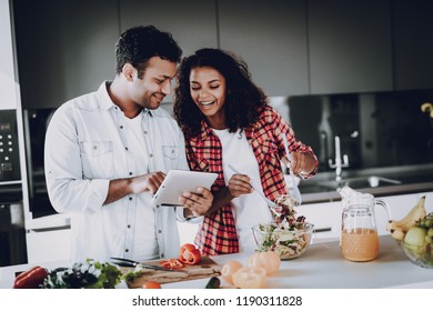 Afro American Happy Couple Cooking At Kitchen. Weekend Concept. Holiday Resting. Smiling Together. Having Fun. Cheerful Sweethearts. Time To Breakfast. Healthy Lifestyle. Tablet Screen.